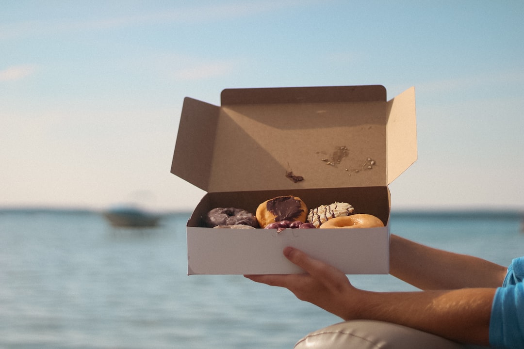 Hands opening a Doughnut Shack delivery box revealing fresh artisan doughnuts